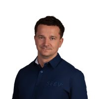 SEEV – Krzesimir www Uśmiechnięty mężczyzna w średnim wieku. Ma na sobie granatową koszulę.