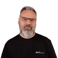 Siwy mężczyzna z brodą. Nosi okulary